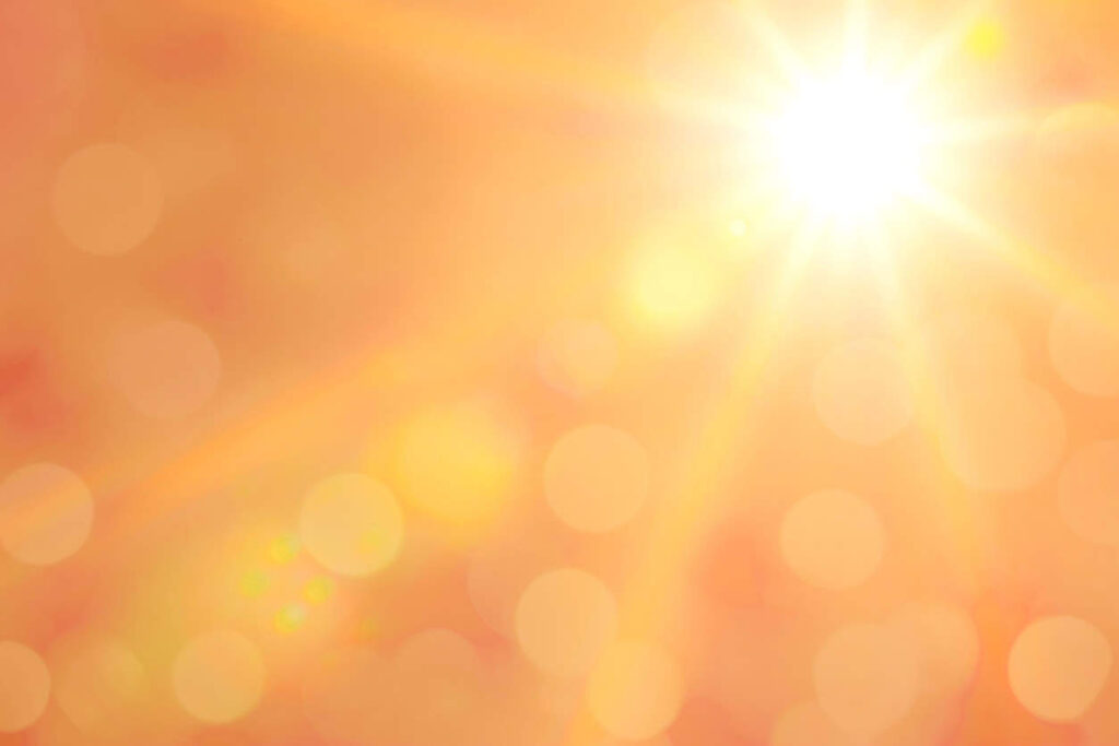 Bright sun with beams and bokeh light in the sky (toned image)