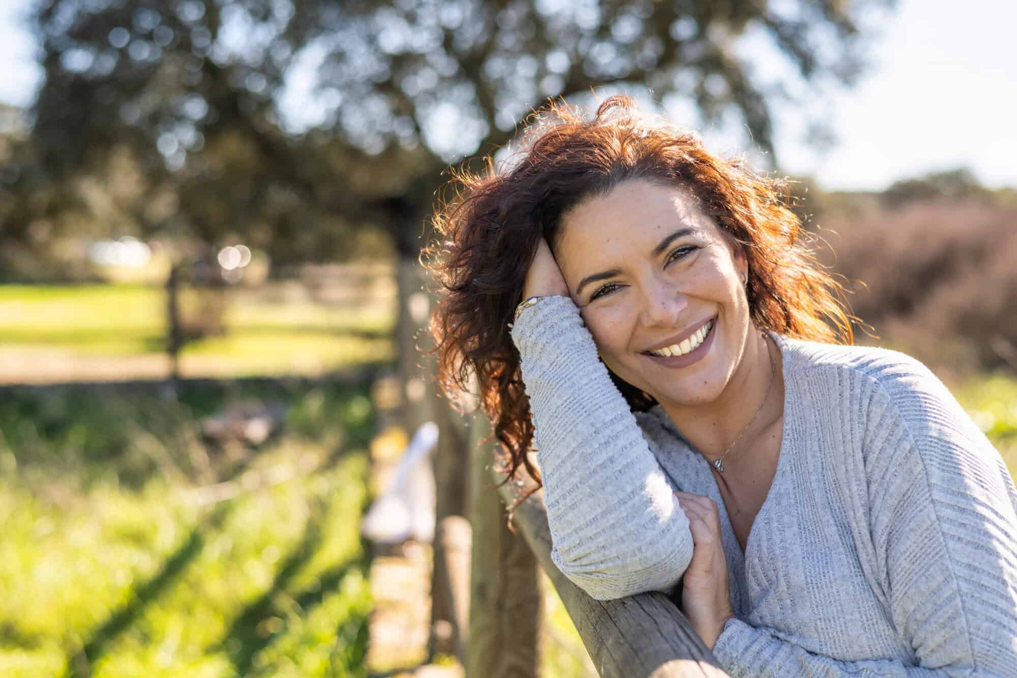 Woman Looking At Camera And Smiling With Positive Emotion. Nature Background